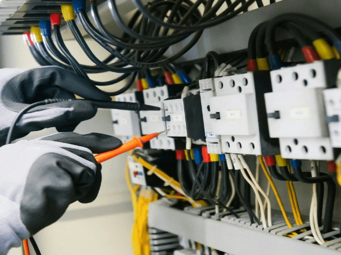 Technicien testant un panneau de contrôle électrique avec un multimètre